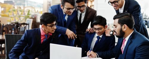 Collaborative process of indian business mans during brainstorming meeting in office.Diverse team of young people dressed in suits cooperating on developing common project.